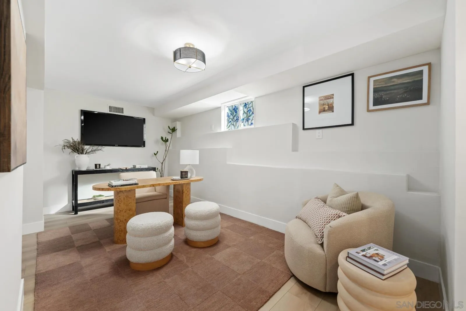 Furnished living room with a curved cream sofa, wood table, and wall-mounted television.