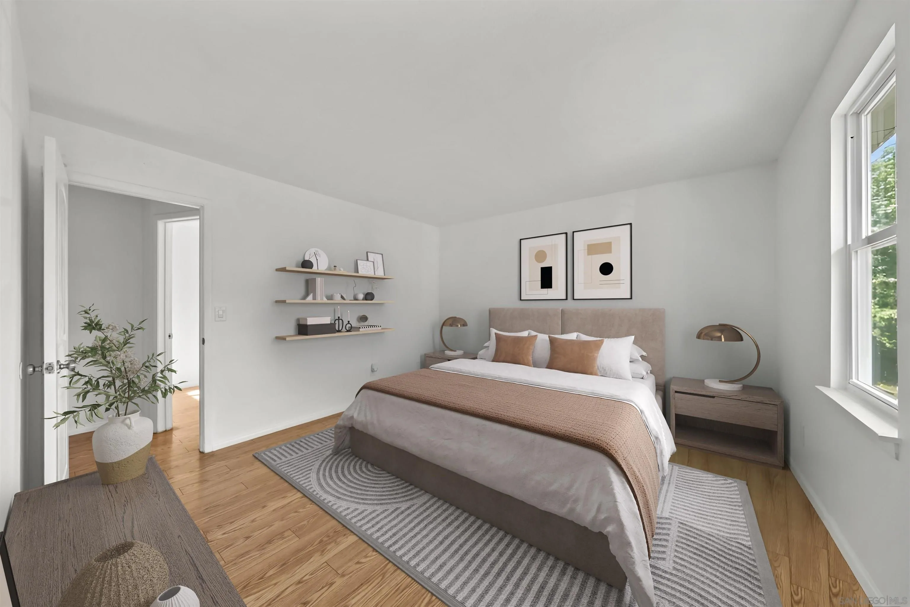 Staged bedroom with a centered bed, floating shelves, and a large window overlooking greenery.