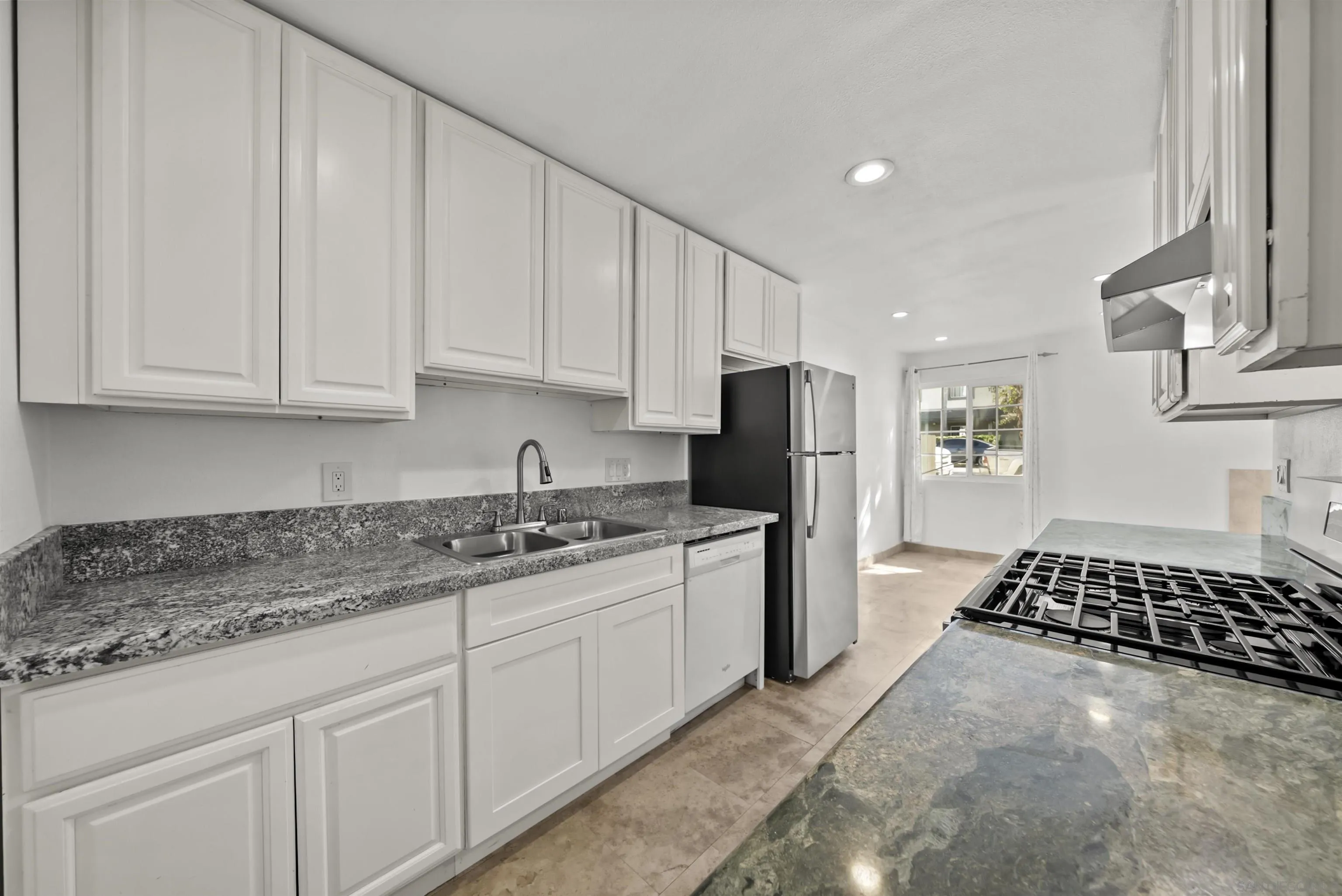 Kitchen with white cabinets, gray granite counters, a double sink, and stainless steel appliances.