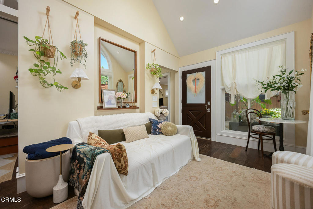 Living room with a white-covered sofa, hanging plants, and a window-side table.