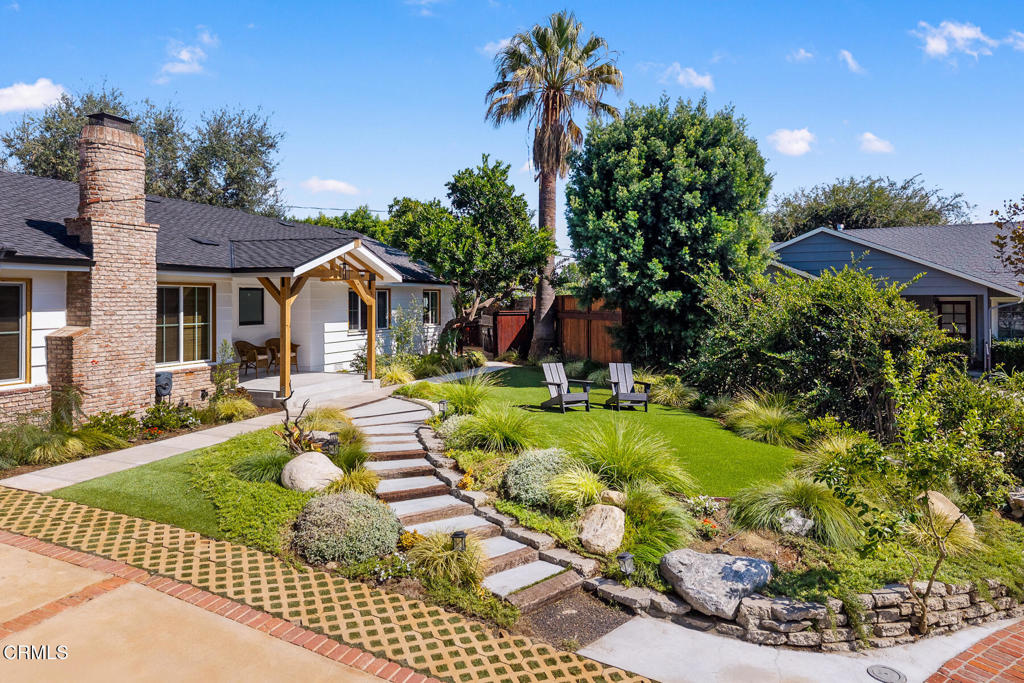 Home with a landscaped front yard, stepping-stone path, and two patio chairs.