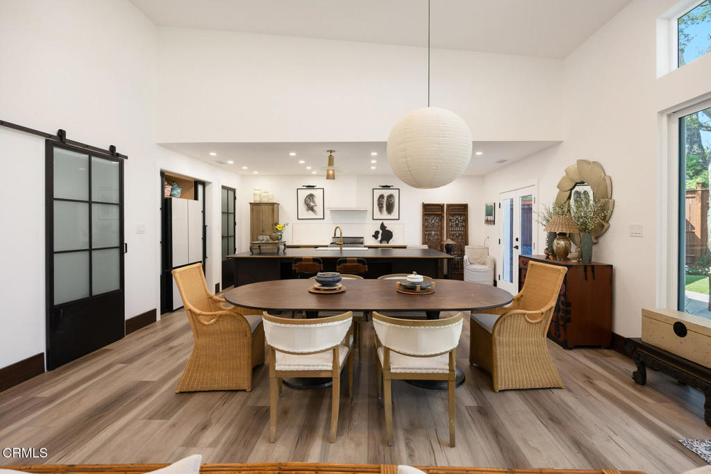 Dining area with an oval wooden table, wicker chairs, and an open kitchen.