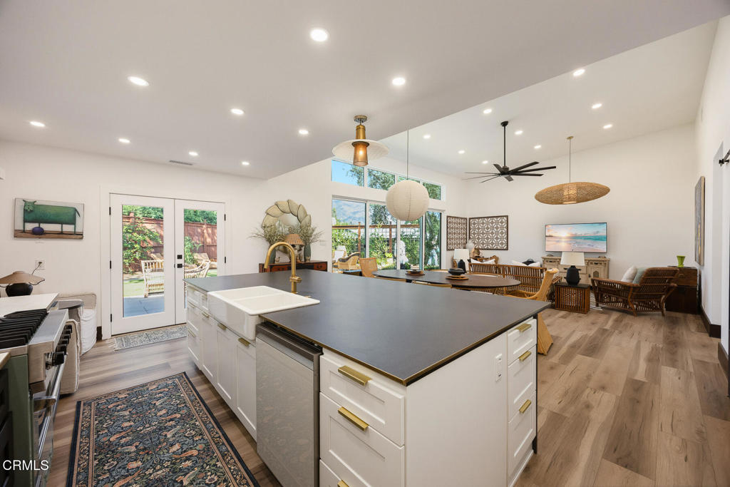 Open-plan kitchen with a large island and furnished living area beside garden-facing glass doors.