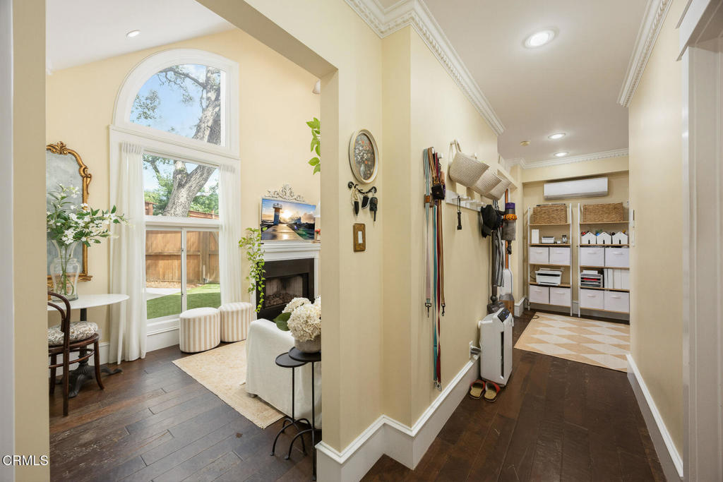 Living room and hallway with arched windows, a fireplace, wall hooks, and built-in storage shelves.