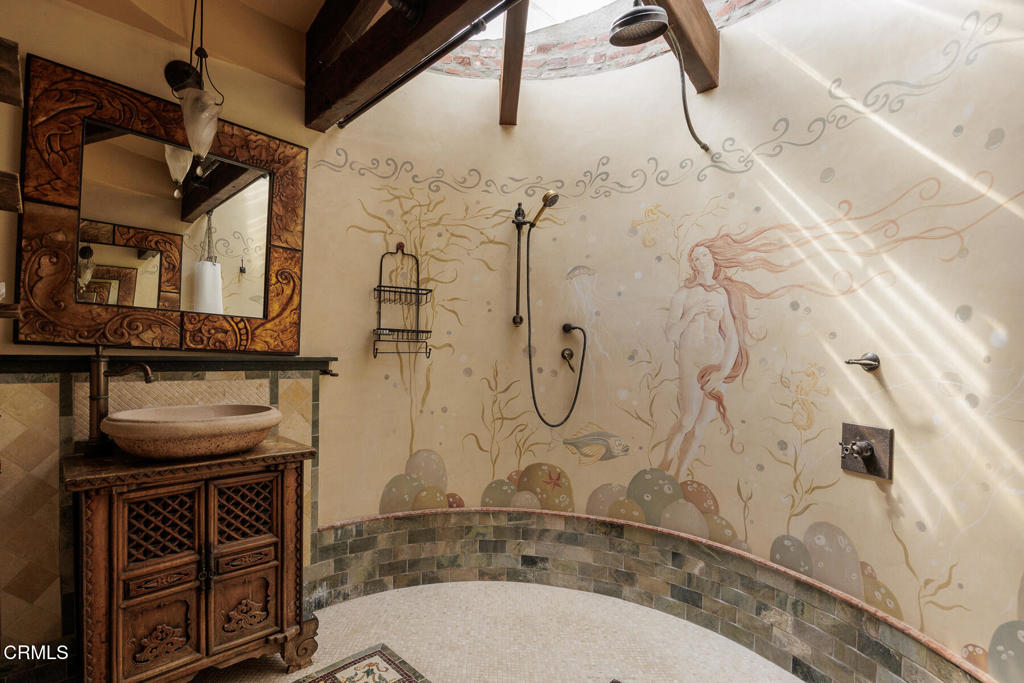 Bathroom with a mural-lined curved shower and an ornate carved-wood vanity.
