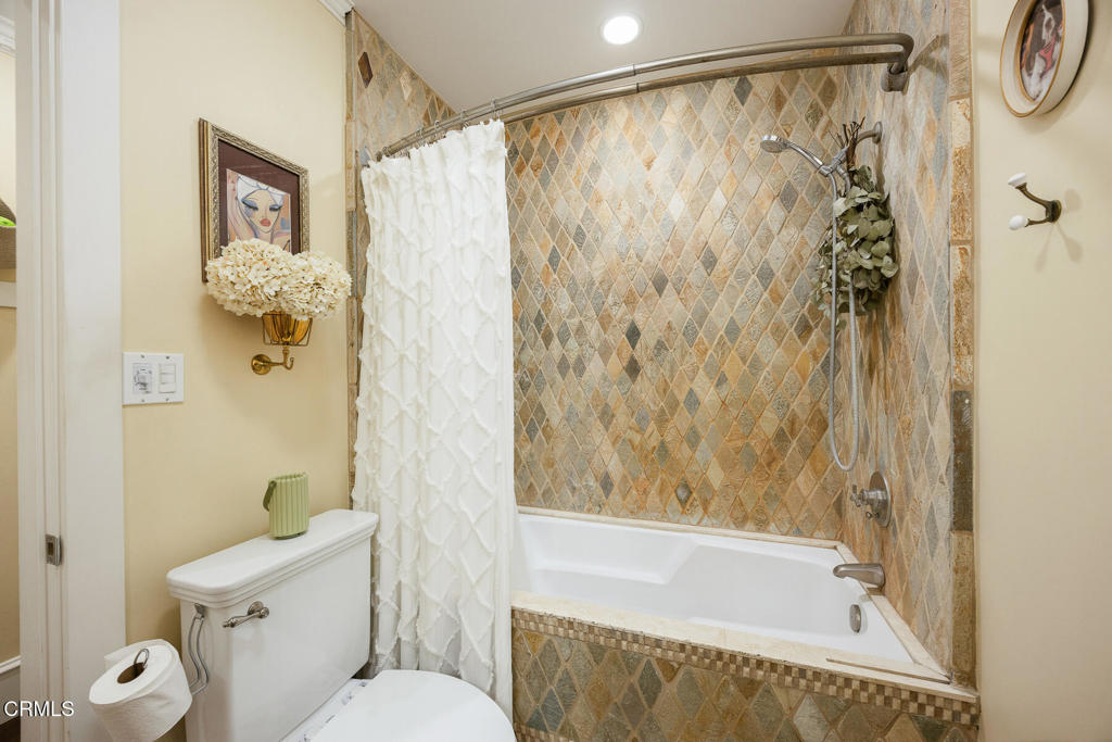 Bathroom with a bathtub, white shower curtain, and tan diamond-pattern tile surround.