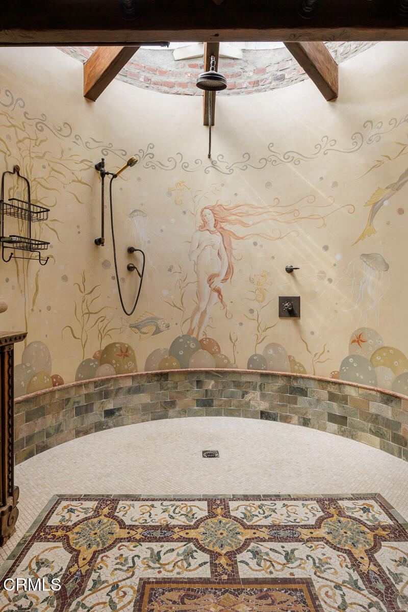 Walk-in shower with an underwater mural, curved stone-tile walls and an intricate mosaic floor.