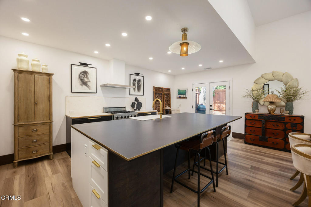 Kitchen with a large dark island, bar seating, and stainless steel range.
