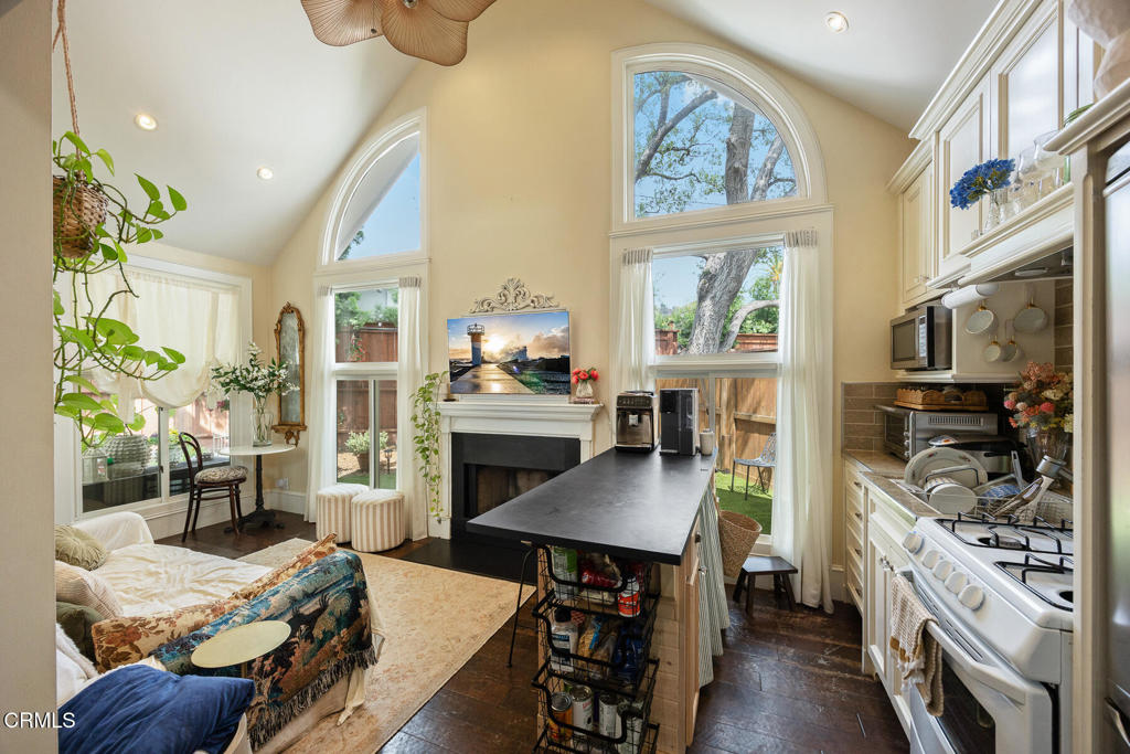Open-plan kitchen and living area with a black island, white cabinetry, and tall arched windows.