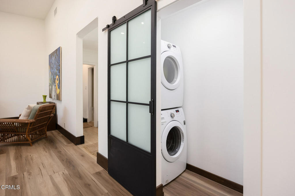 Laundry area with stacked washer and dryer behind a black-framed frosted-glass barn door.