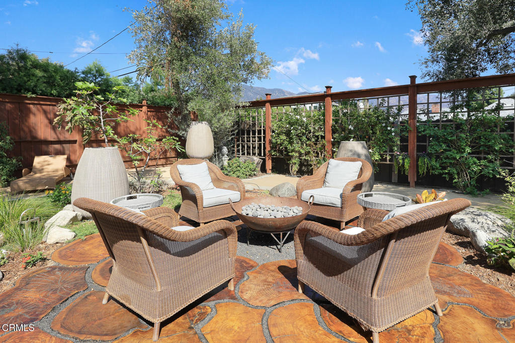 Furnished patio with wicker seating, a central fire bowl, and patterned stone flooring.