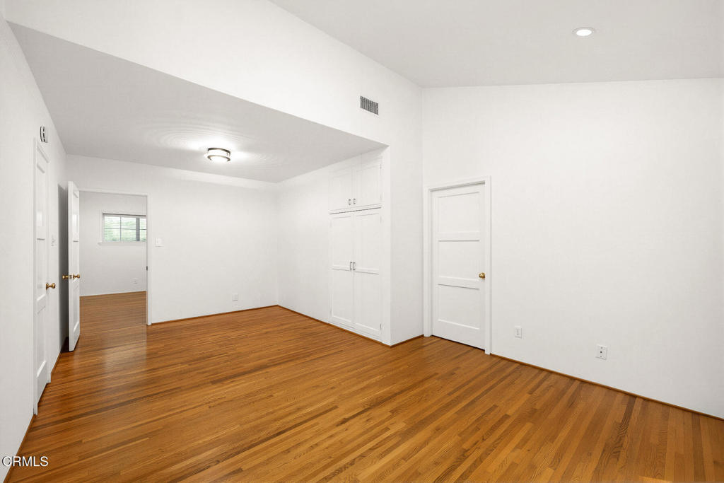 Unfurnished bedroom with hardwood floors, a built-in closet, and a small window.