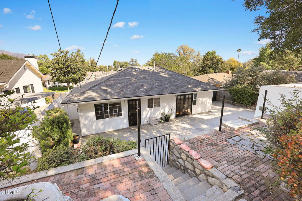 Single-story home with a broad paved rear patio, brick paths, and stone steps.