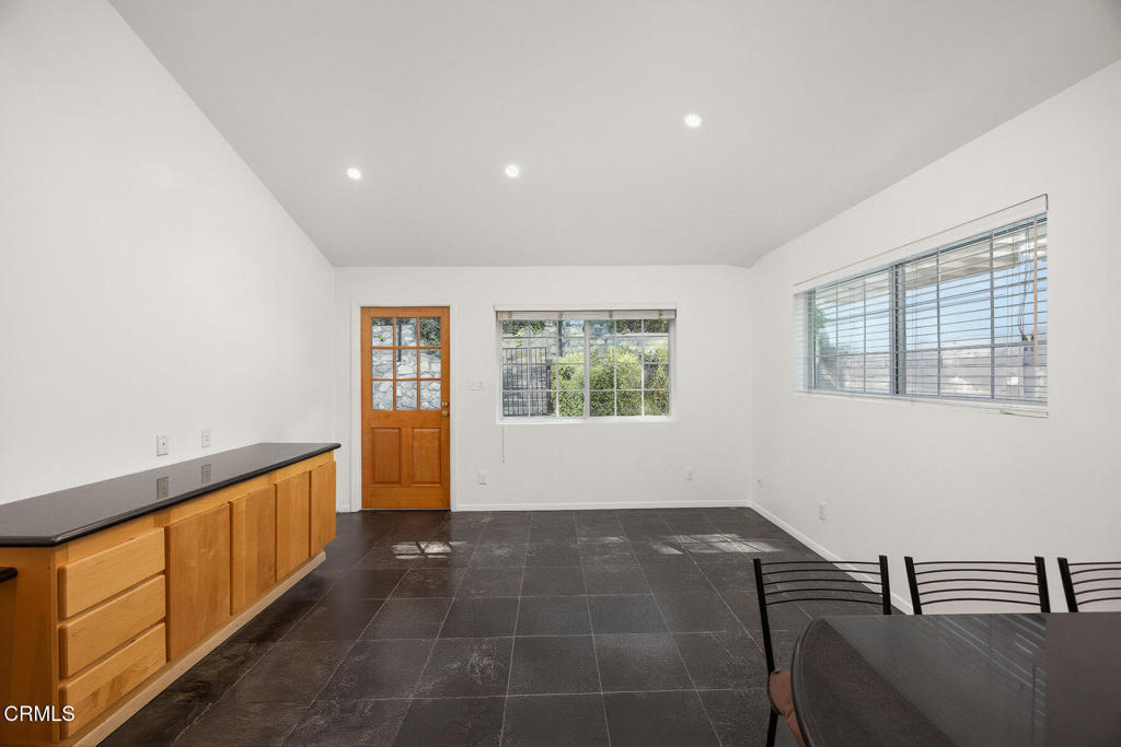 Dining room with dark tile floors, built-in wood cabinets, and windows on two walls.