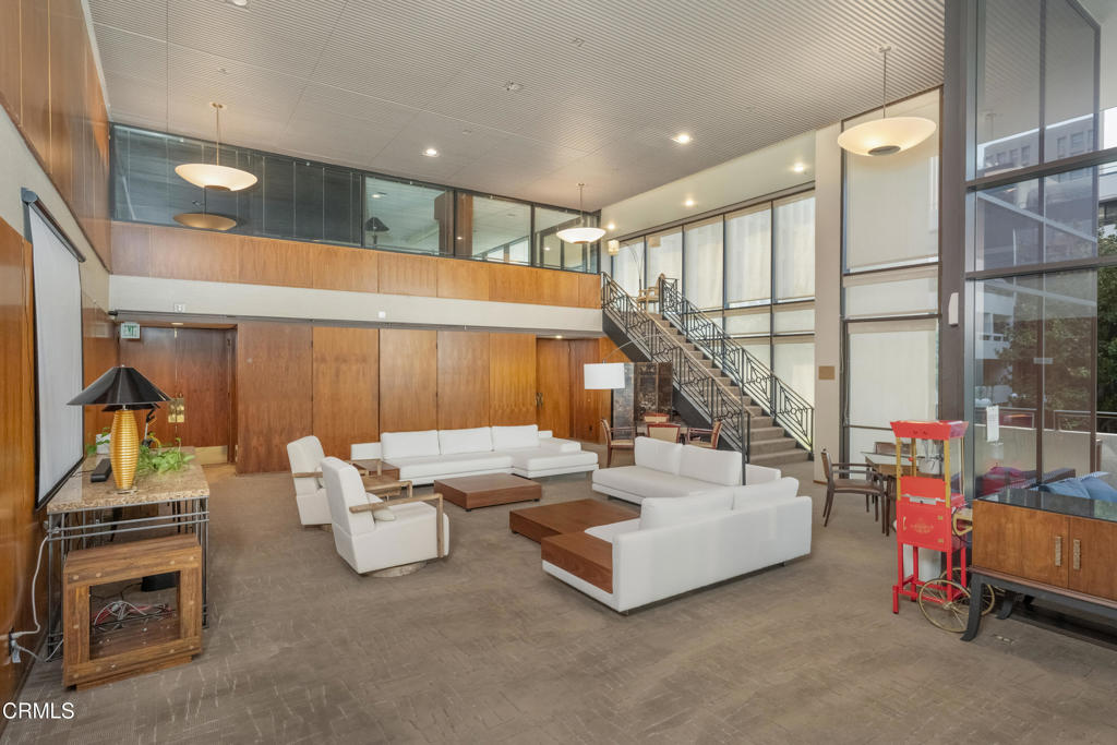 Residential lobby lounge with white seating, wood-paneled walls, and a staircase.