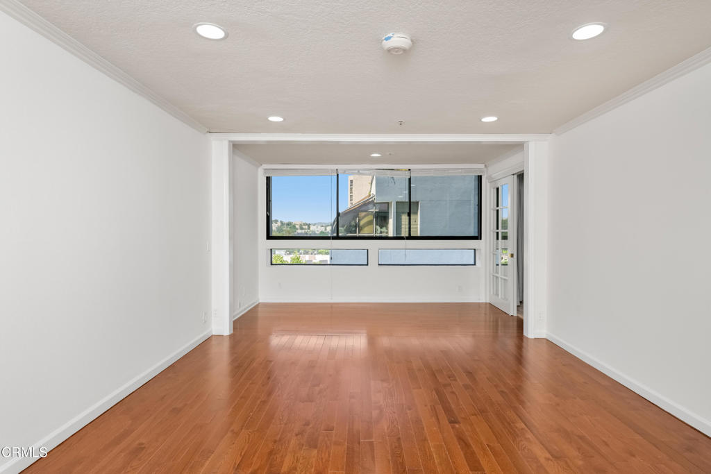 Vacant condo living area with hardwood floors and large windows.