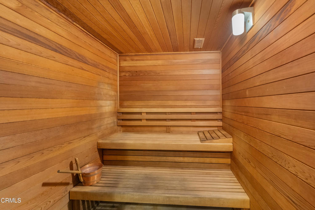 Wood-paneled sauna with two built-in benches and a bucket and ladle.