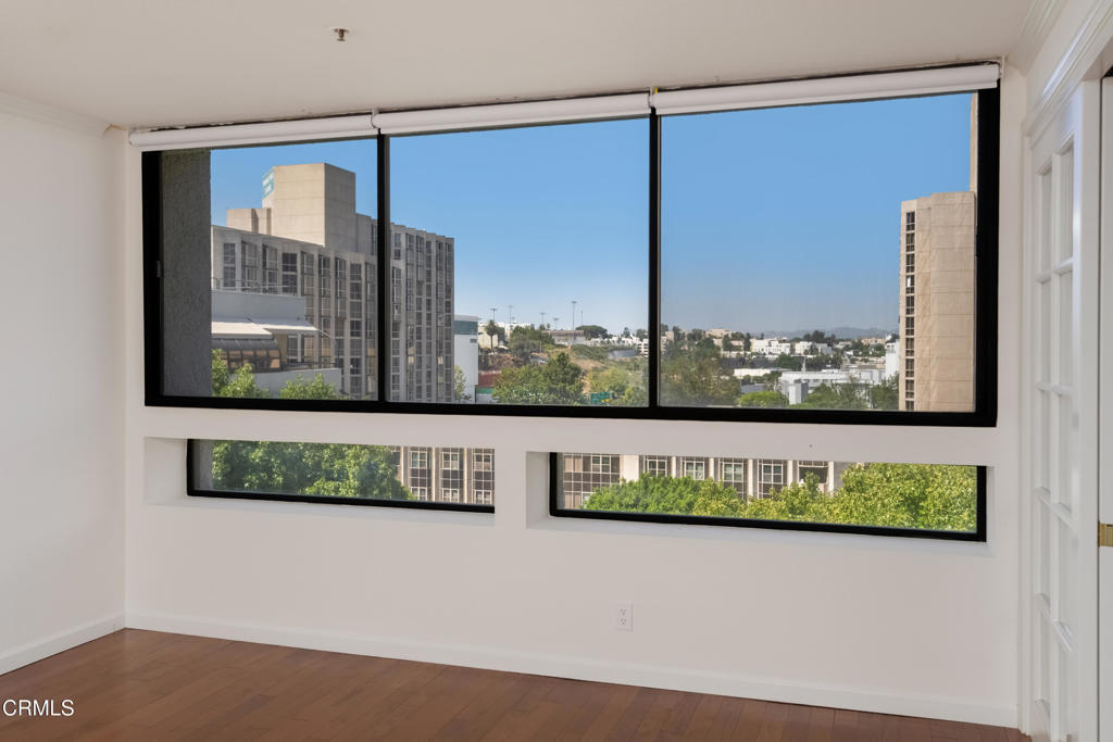 Vacant room with wood flooring and wide windows overlooking downtown Los Angeles.