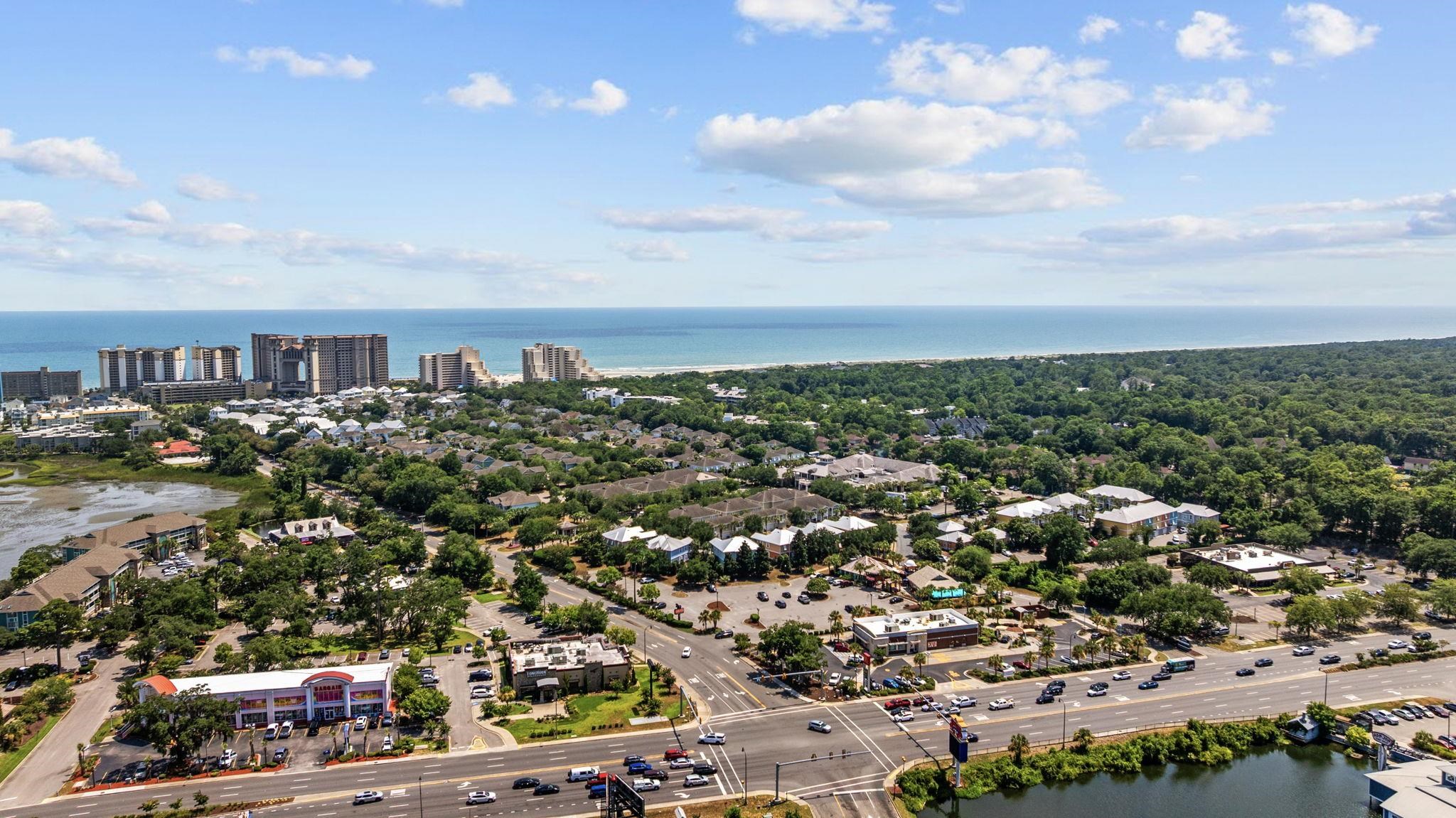 Aerial view of a North Myrtle Beach neighborhood, with the ocean, beachside towers, and busy road.