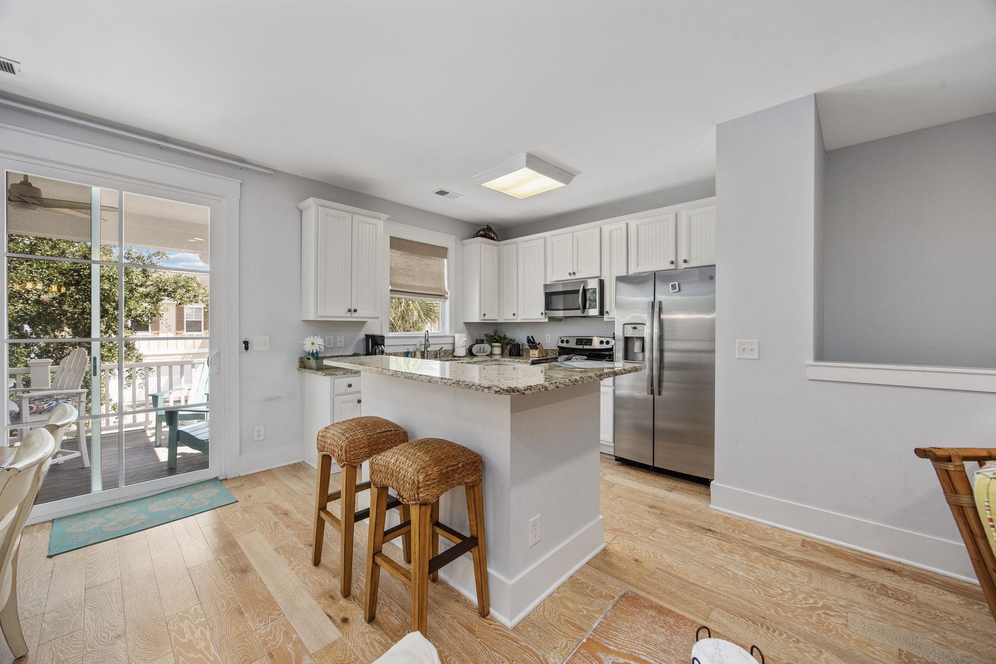 Kitchen with white cabinets, granite peninsula, stainless steel appliances, and sliding doors to a deck.