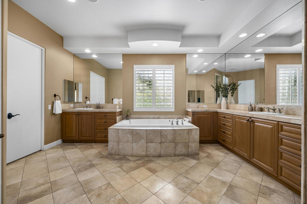 Bathroom with a central soaking tub, mirrored walls, and wood vanities.
