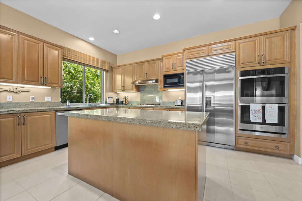 Kitchen with a large wood-paneled island, granite counters, and stainless steel appliances.
