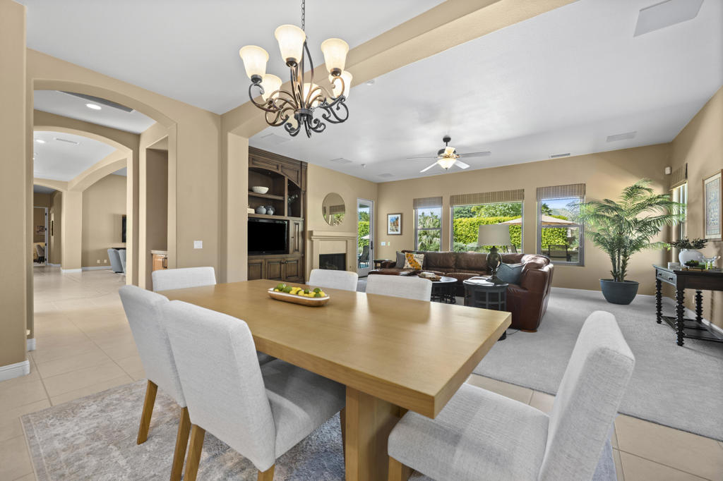 Open dining and living area with a long wood table, fireplace, and large windows.