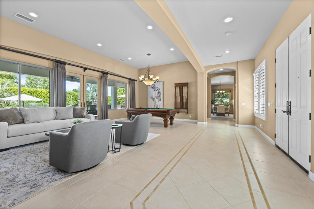 Living room with gray seating, a pool table, and an entryway opening toward the dining area.