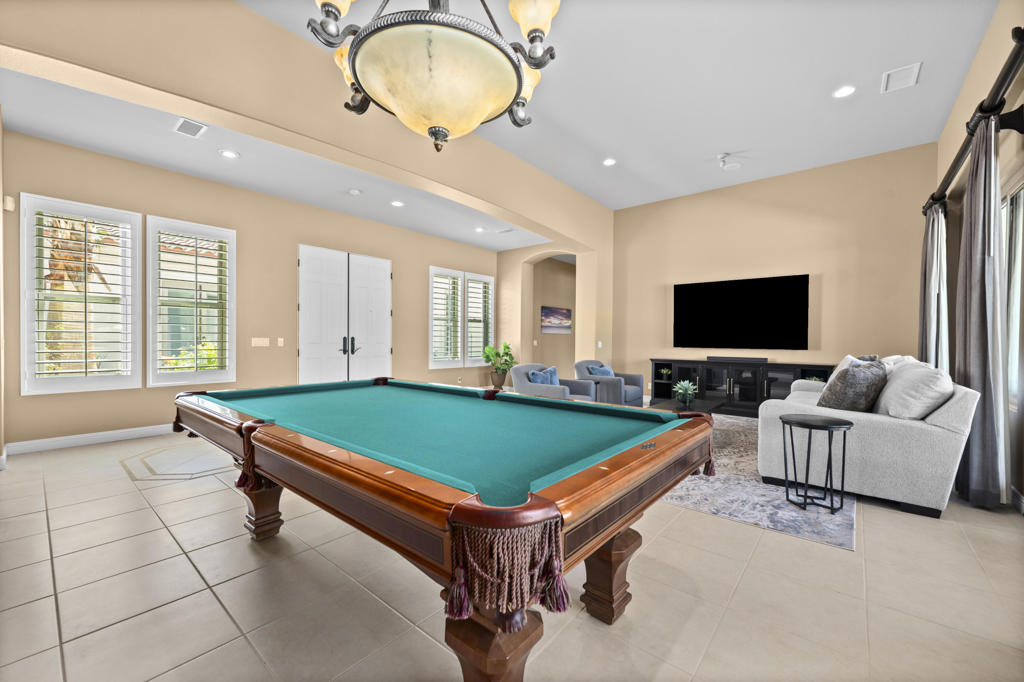 Game room with a turquoise-felt pool table, lounge seating, and a wall-mounted television.