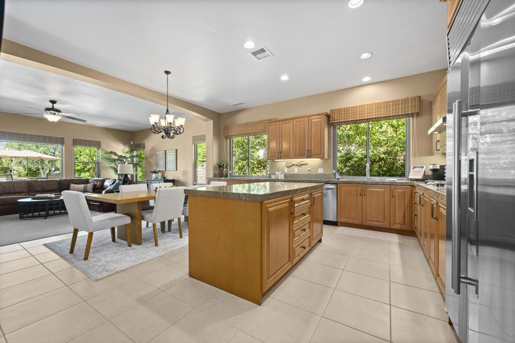 Open kitchen with a large central island, wood cabinetry, and adjoining dining and living areas.