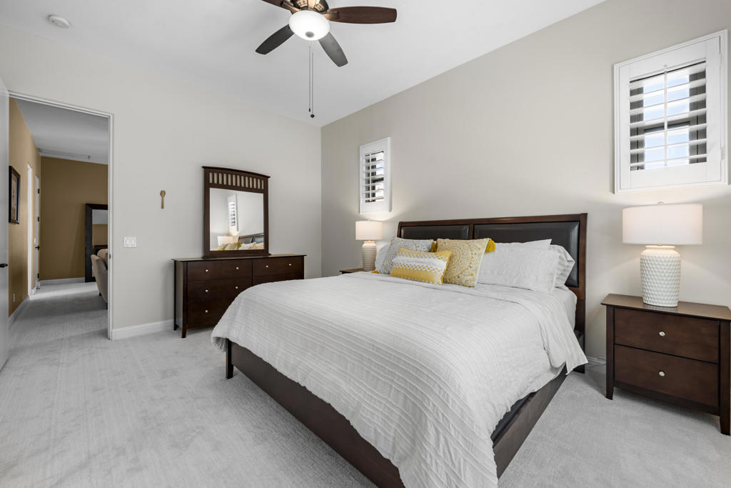 Primary bedroom with a dark wood bed, white bedding, and plantation shutters.