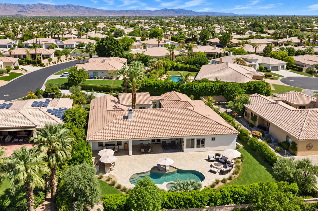 Aerial view of a La Quinta home with a curved pool, landscaped patio, and mountain backdrop.