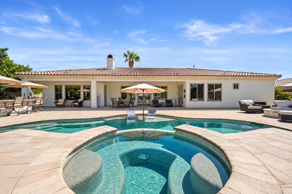 Backyard pool and spa with curved submerged seating, patio furniture, and a single-story home.