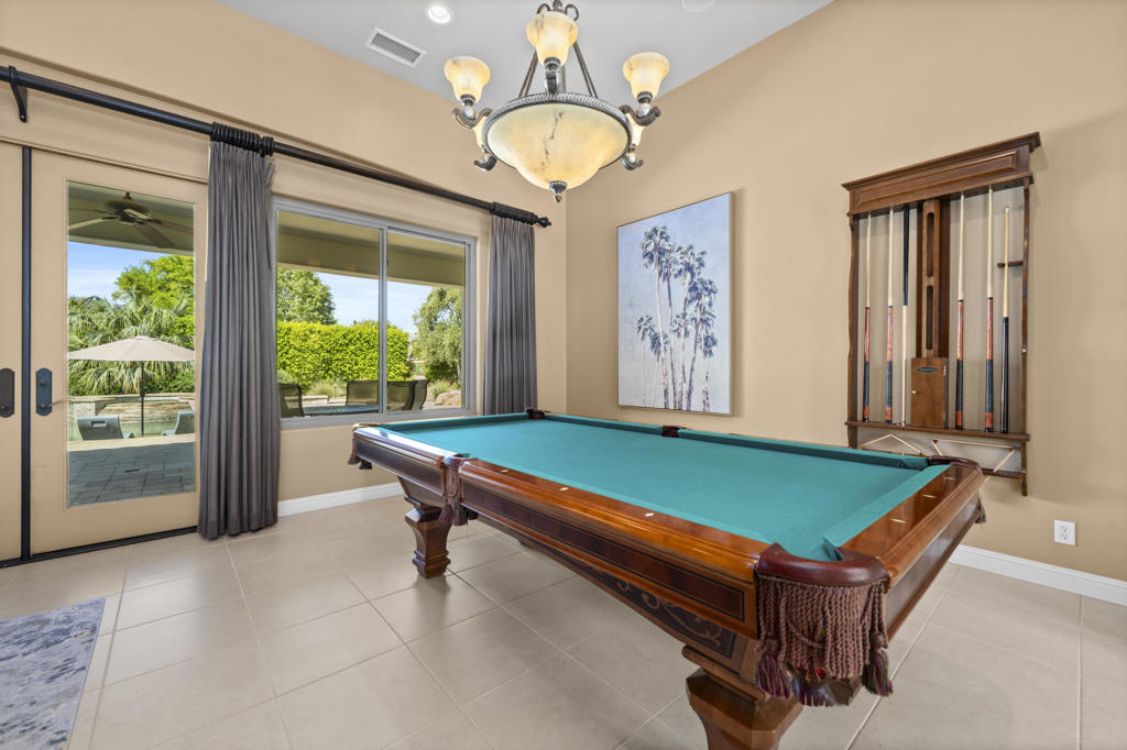 Billiards room with a turquoise pool table, cue rack, and glass doors to the patio.