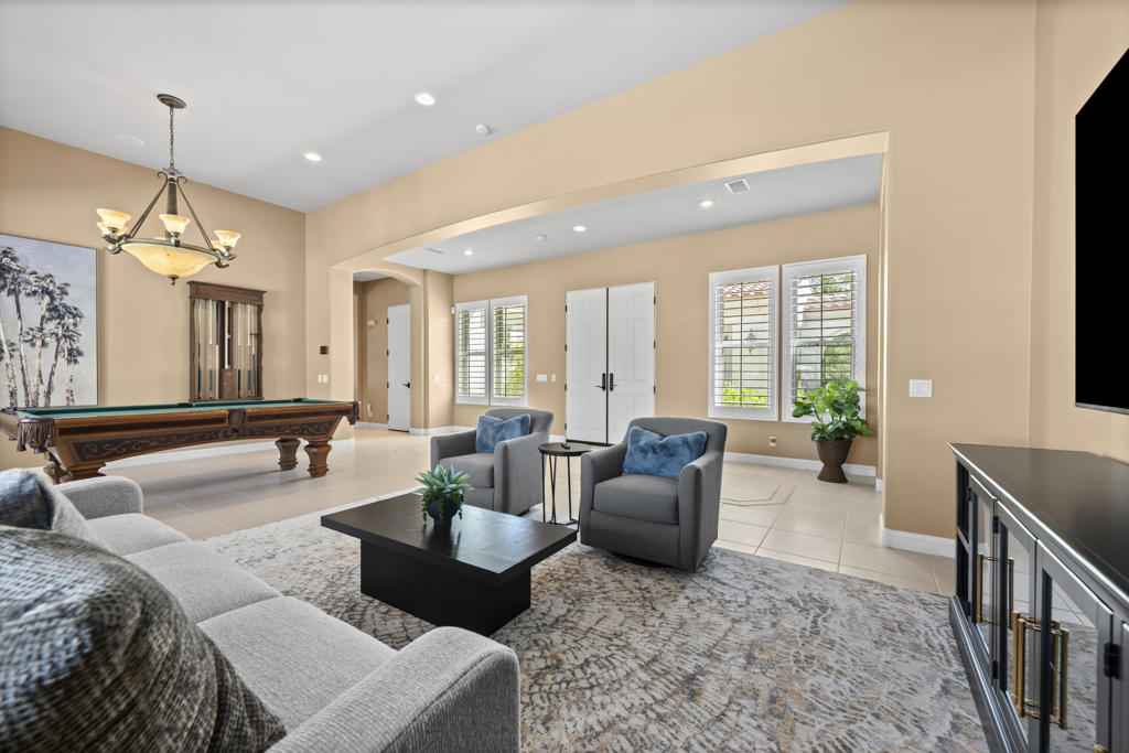Open game room with a pool table, seating area, and shuttered windows.