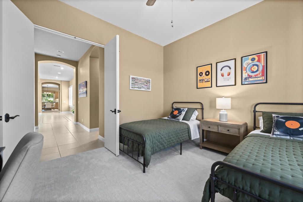 Bedroom with two twin beds, record-themed wall art, and an open doorway to the hallway.