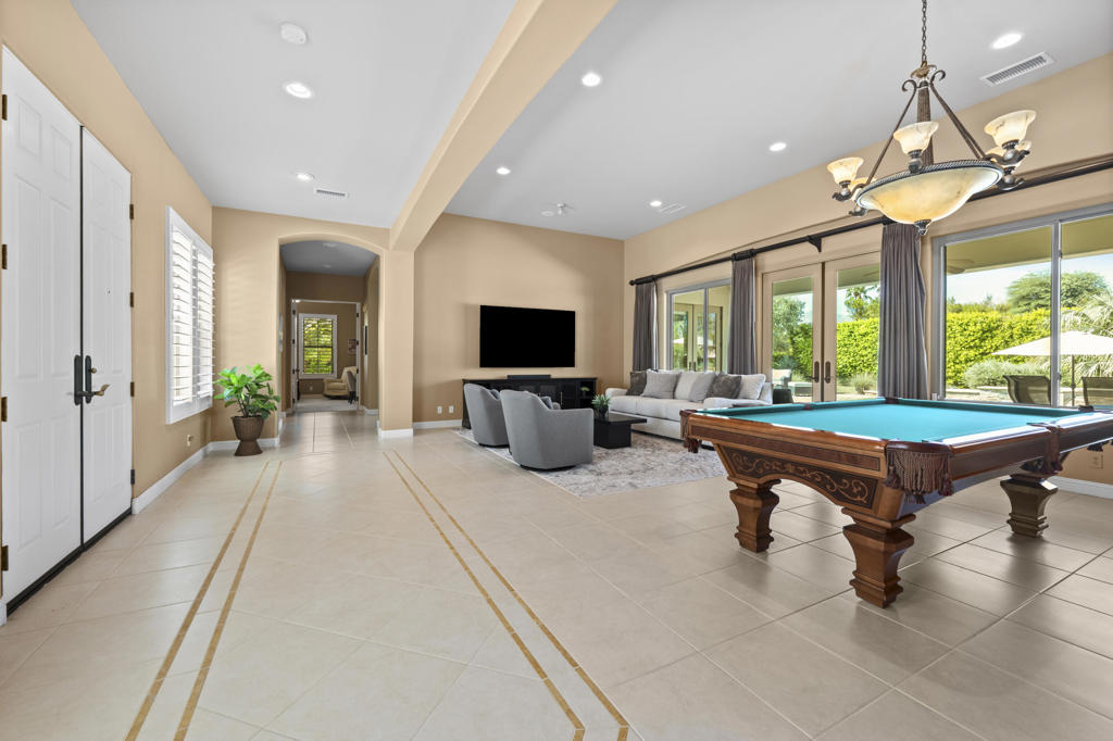 Game room with a billiards table, seating area, and large windows overlooking greenery.