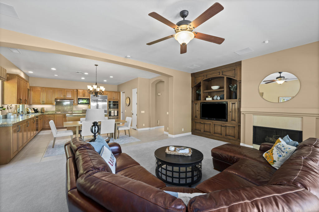 Open living room with leather sectional, fireplace, and adjoining kitchen and dining area.
