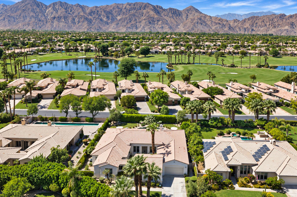 La Quinta homes beside a golf course lake, with palm trees and mountains beyond.