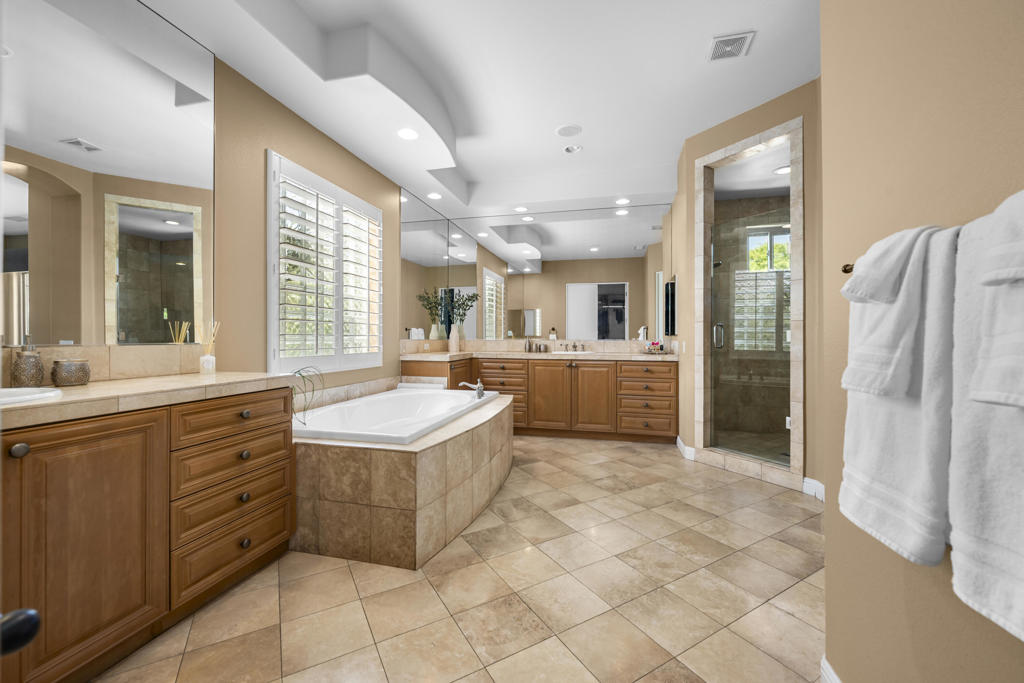 Bathroom with a large soaking tub, wood vanities, and a glass-enclosed shower.