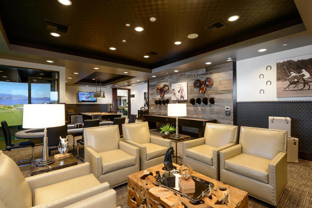 Furnished lounge with cream leather chairs, a pool table, and a rustic wood accent wall.