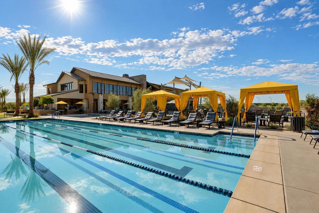 Outdoor lap pool with yellow cabanas and lounge chairs beside a modern building.