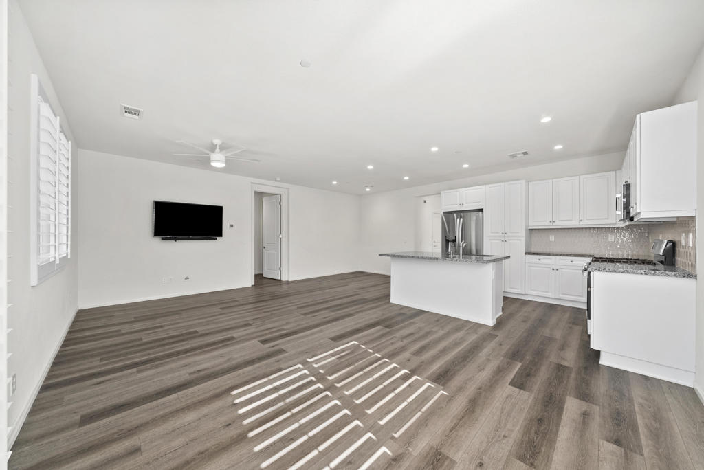 Open-plan living room and kitchen with white cabinetry, island, and wood-look flooring.