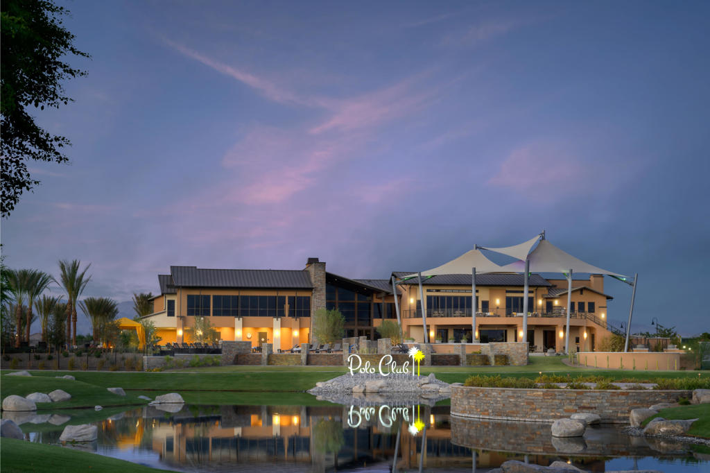 Polo Club clubhouse beside a reflecting pond at dusk.