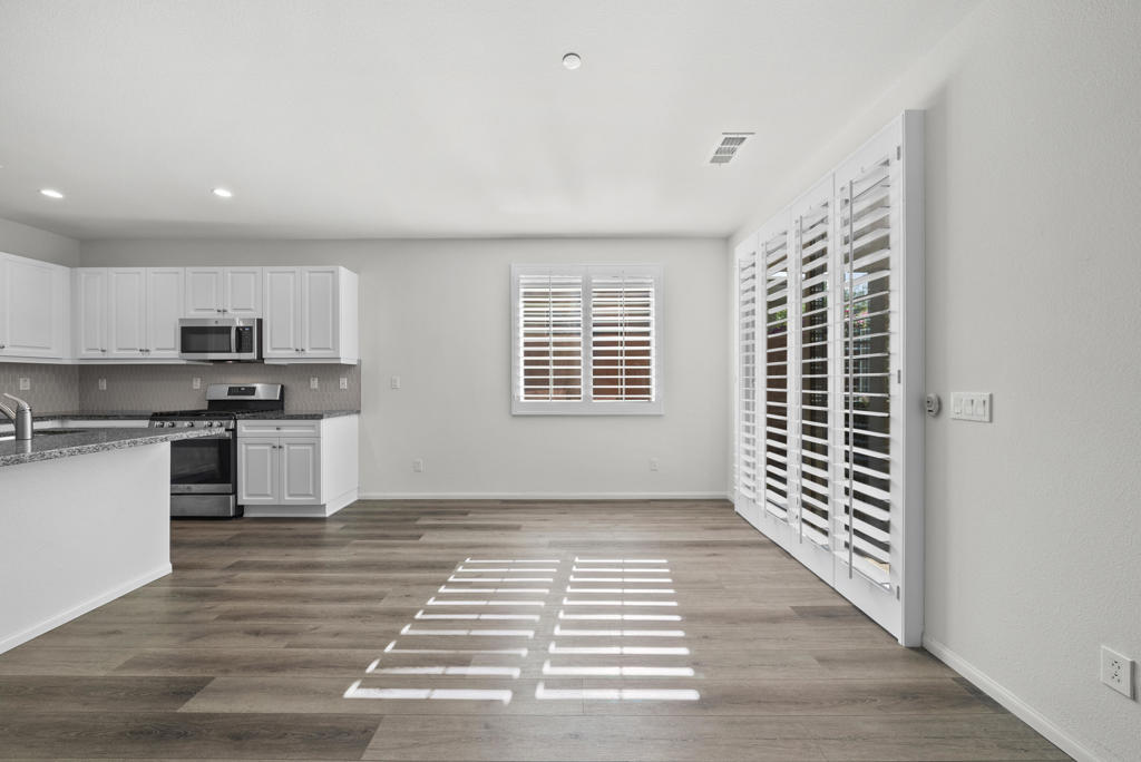 Kitchen and dining area with white cabinets, stainless steel appliances, and plantation shutters.