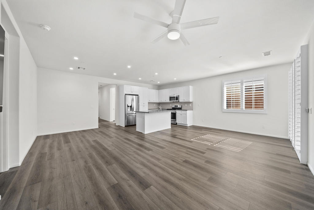 Open living area and kitchen with white cabinets, a peninsula, and wood-look flooring.