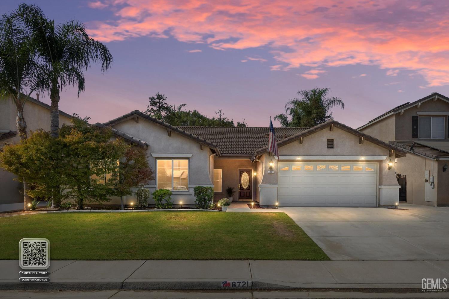 Single-story stucco home with a tiled roof, two-car garage, and landscaped lawn at dusk.
