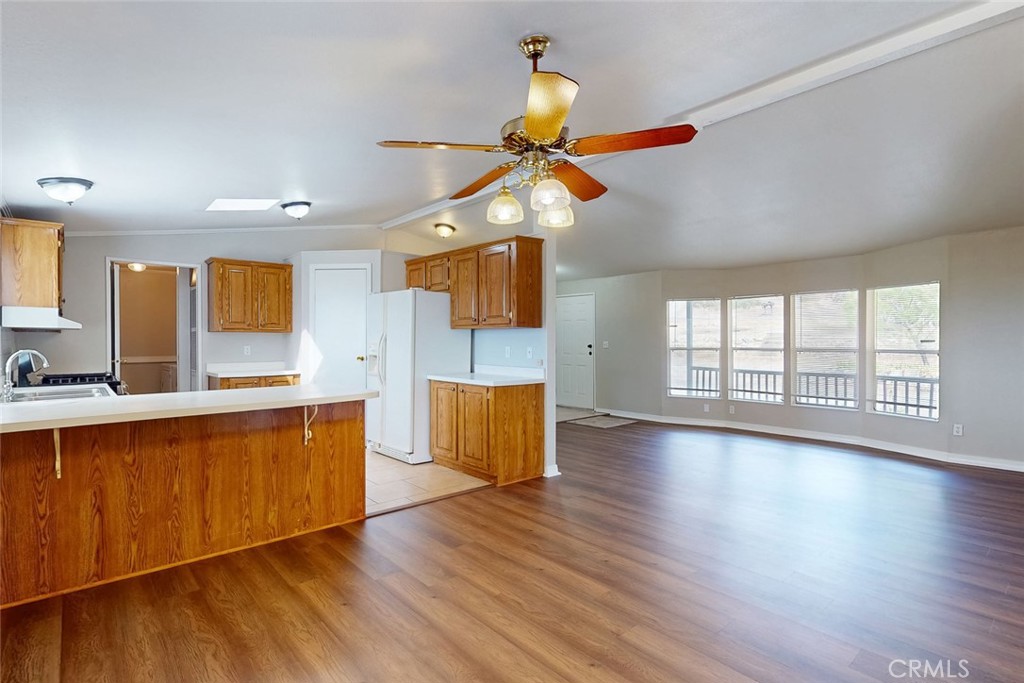 Open kitchen and living area with wood cabinets, breakfast bar, and wide windows.