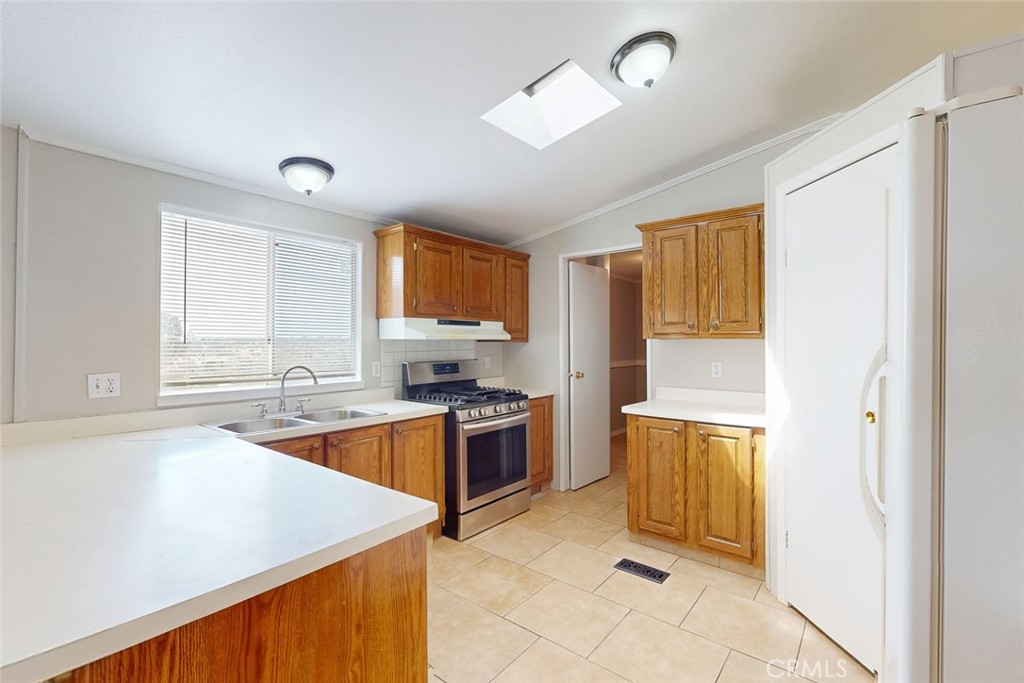 Vacant kitchen with wood cabinets, white counters, and a stainless steel range.