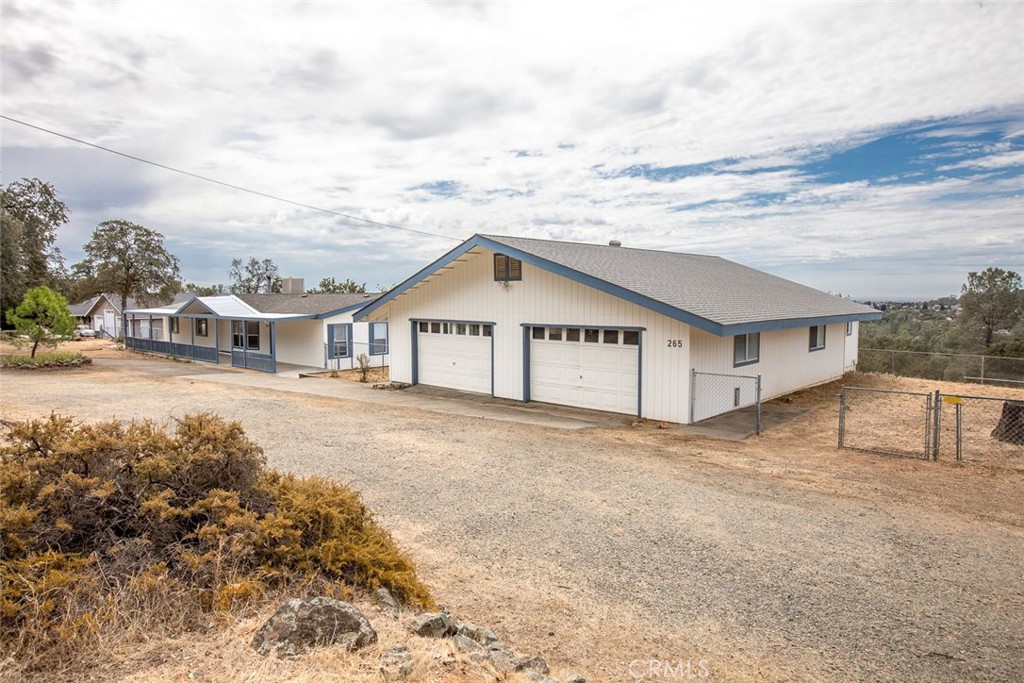 Single-story white house with blue trim, two-car garage, and broad gravel driveway.